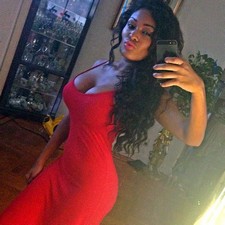 Ebony female in sexy red dress is very proud to present us her enormous breasts in front